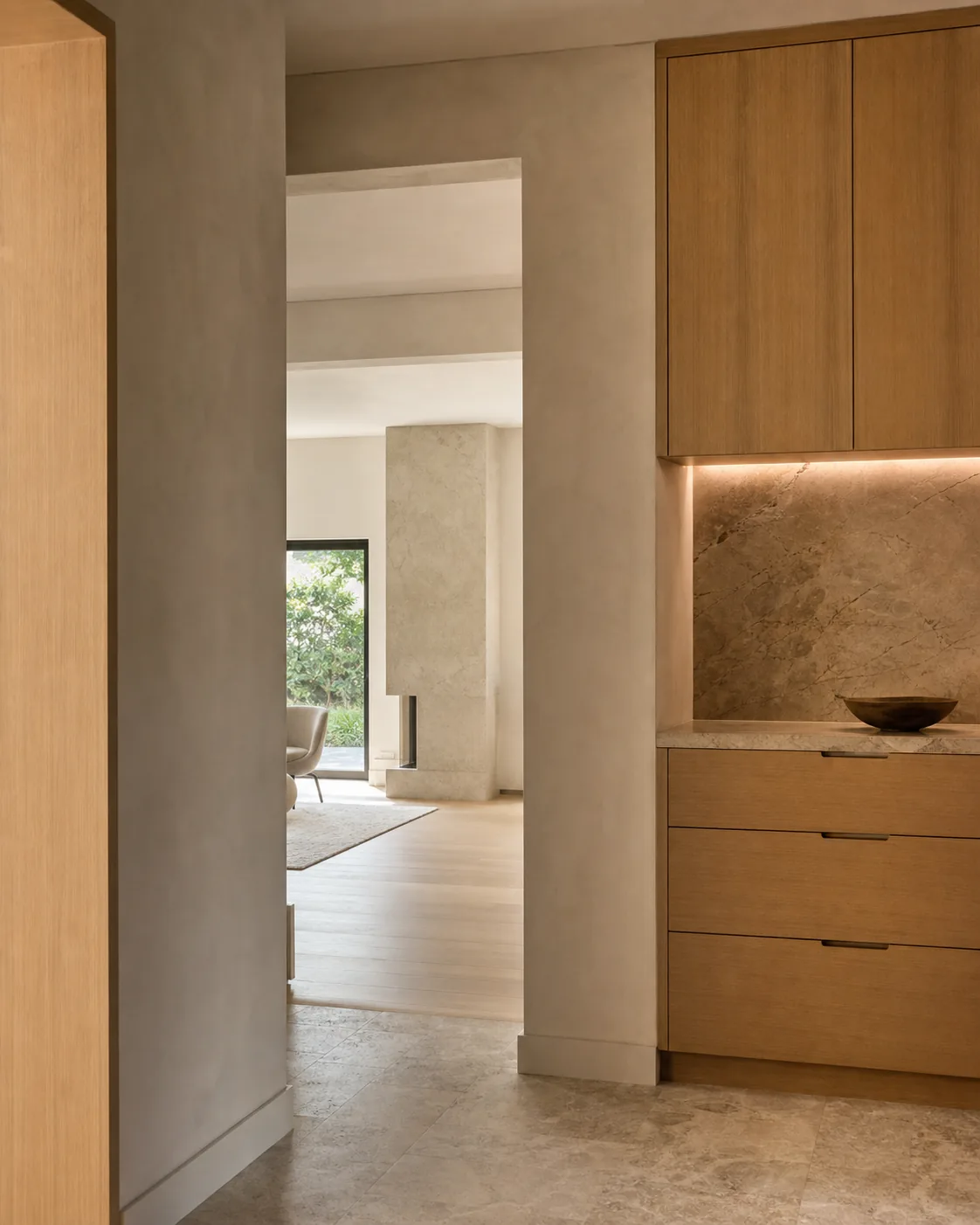 Intérieur résidentiel calme avec menuiserie en bois, pierre naturelle et lumière douce.