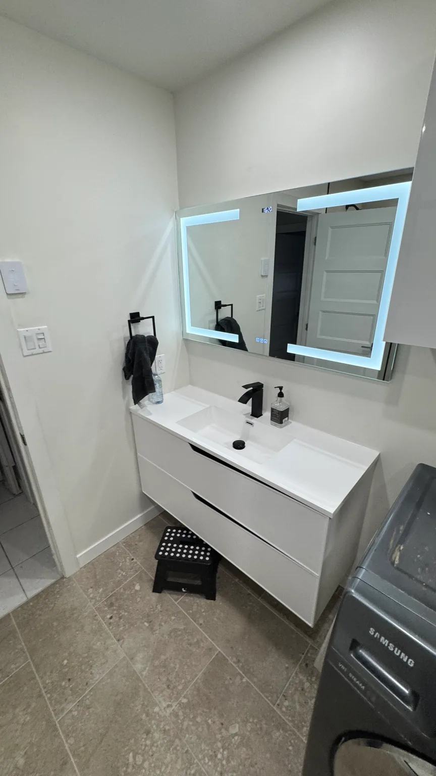 Wall-mounted vanity installed with illuminated mirror and storage cabinets.