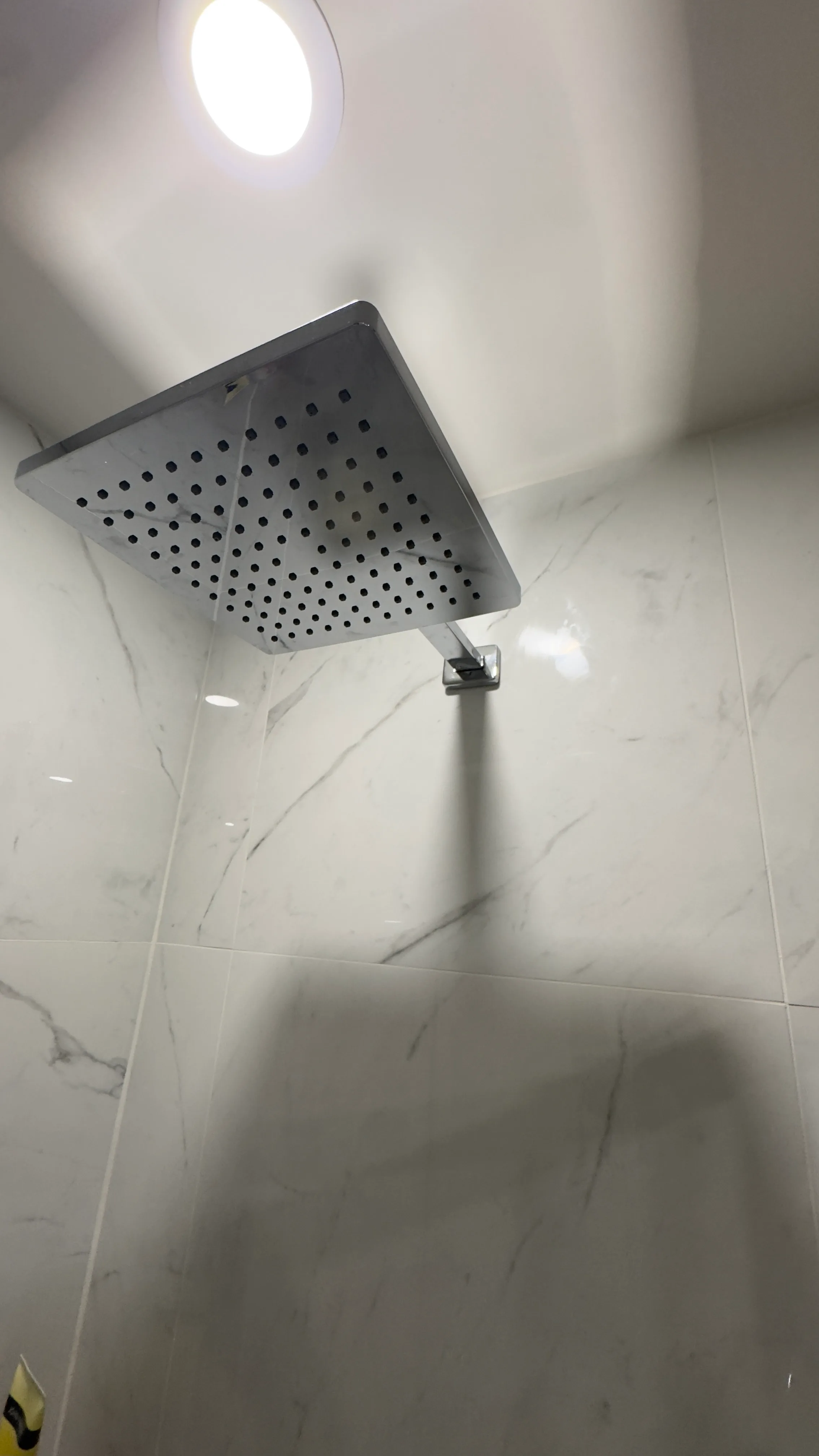 Détail de la tête pluie dans la douche en porcelaine marbrée terminée.